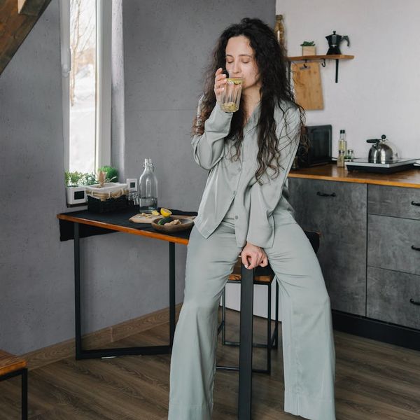 Woman mindfully drinking tea, applying yoga principles to daily life.